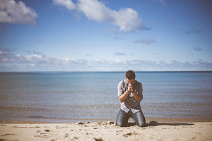 Young Man Praying on the Beach